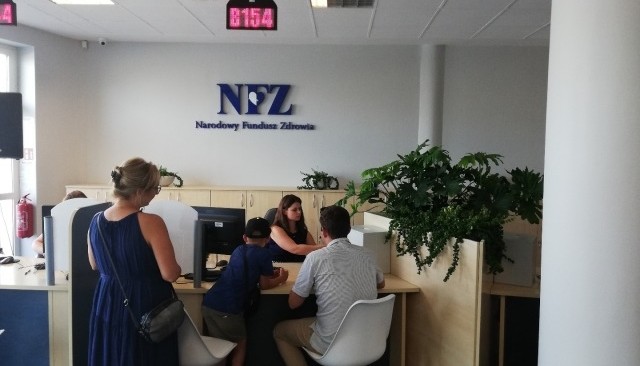 Kolorowa fotografia. Nowy punkt obsługi klienta NFZ w Kielcach. Rodzina oczekuje na wydanie karty EKUZ.
