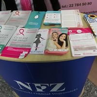 Kolorowa fotografia. Stoisko NFZ z ulotkami na temat profilaktyki raka piersi