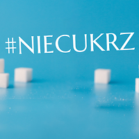 Kolorowa fotografia. Kostki cukru na niebieskim tle oraz napis #NIECUKRZ
